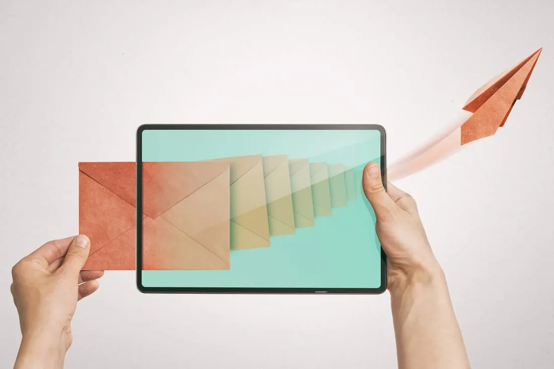 A tablet held in two hands, an envelope transforming into a paper plane flying from the screen